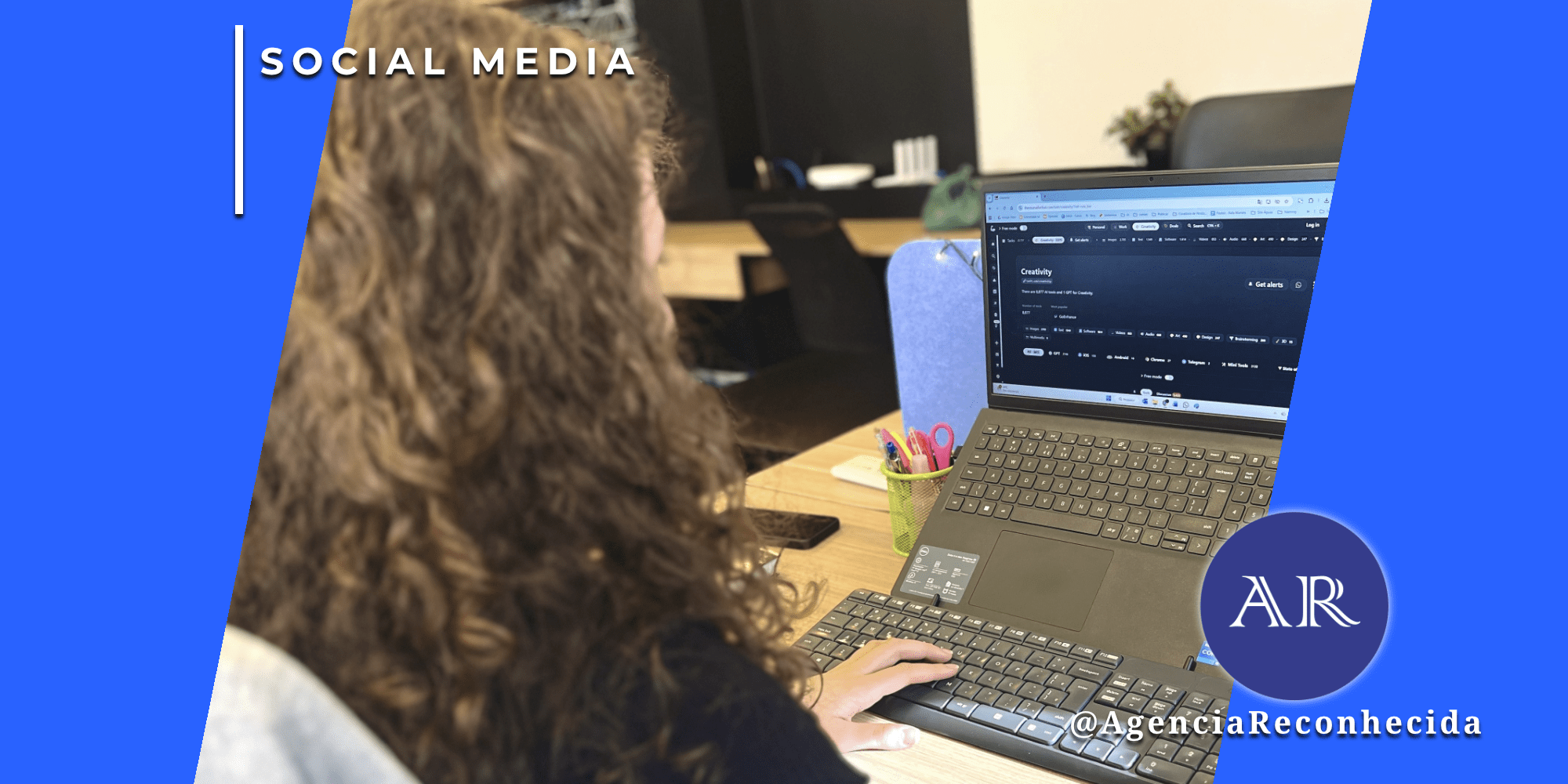 Mulher com cabelos cacheados vista de costas trabalhando em um notebook que exibe uma interface de plataforma de inteligência artificial em um escritório moderno, com o selo da Agência Reconhecida.