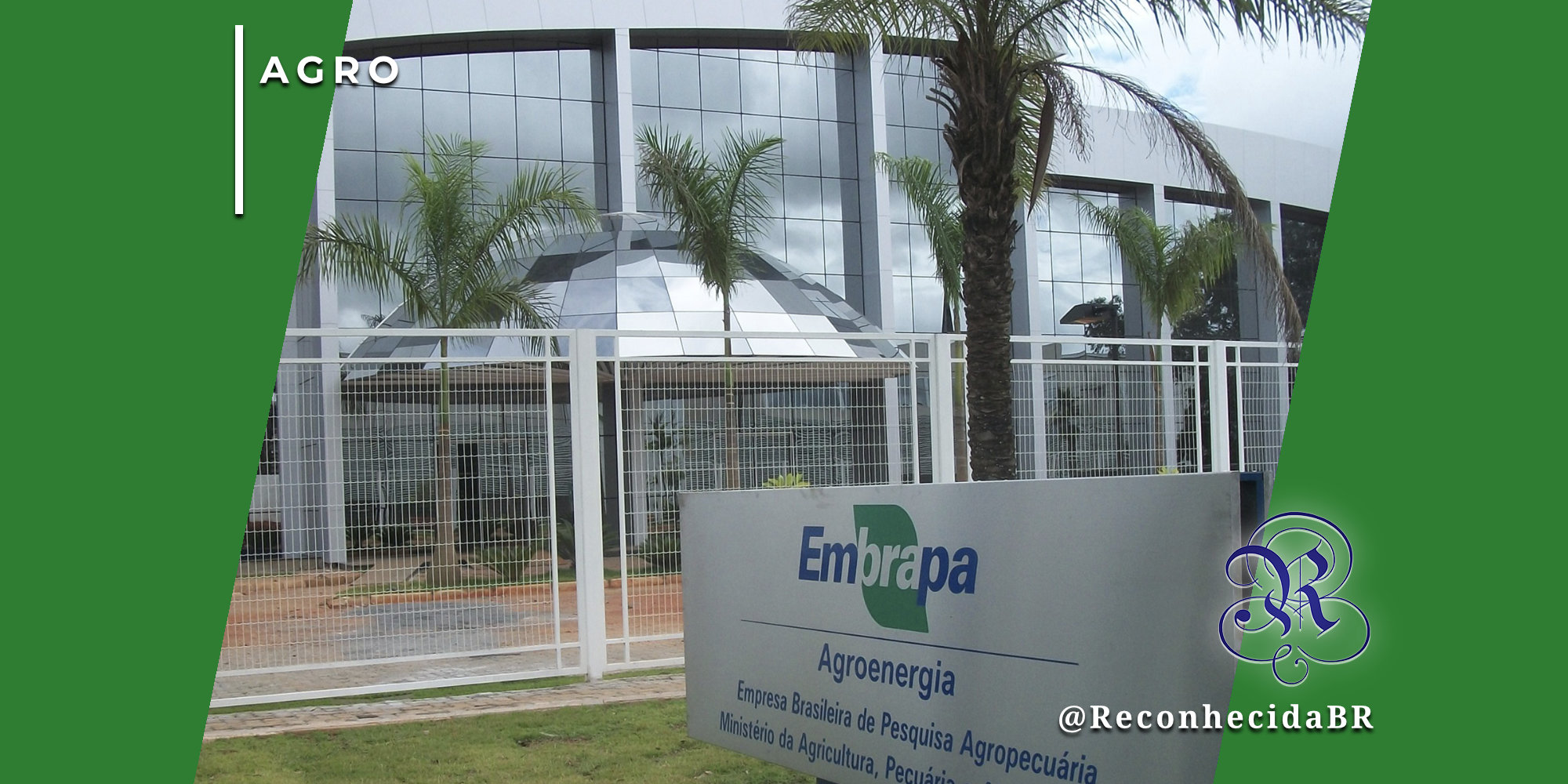 Fachada moderna do prédio da Embrapa Agroenergia (Empresa Brasileira de Pesquisa Agropecuária) sob um céu parcialmente nublado, com palmeiras e jardins à frente. Em primeiro plano, uma placa cinza exibe o logotipo da Embrapa e o Ministério da Agricultura e Pecuária. No canto superior esquerdo, o selo 'AGRO' e, no inferior direito, o logotipo do portal Reconhecida com o @ReconhecidaBR.