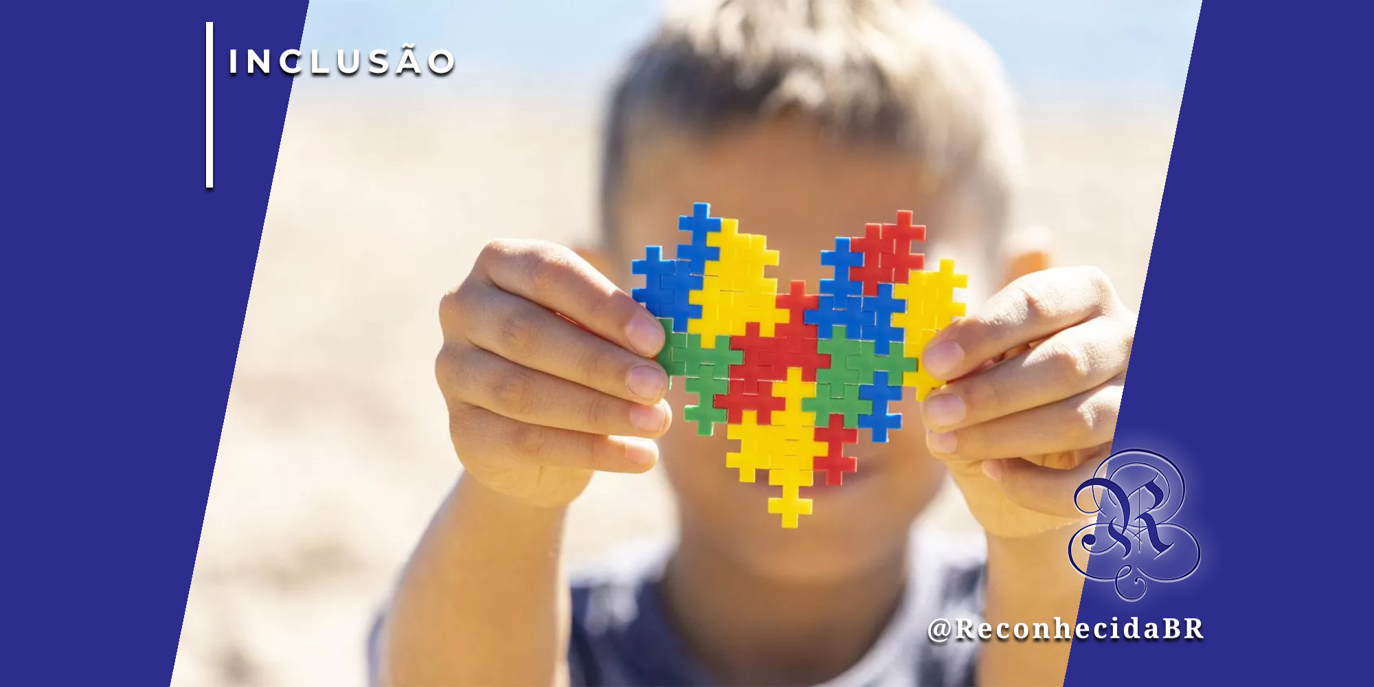 Close-up das mãos de uma criança segurando um coração montado com peças de blocos de encaixe coloridos (azul, amarelo, vermelho e verde), símbolo da conscientização do autismo. Ao fundo, o rosto da criança está desfocado em um ambiente iluminado. No canto superior esquerdo, o selo 'INCLUSÃO' sobre fundo azul e, no inferior direito, o logotipo do portal Reconhecida com o @ReconhecidaBR.