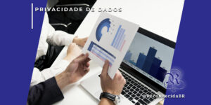 Uma pessoa segura uma folha de papel com gráficos circulares e de barras enquanto analisa dados em um notebook, que exibe um gráfico de barras azul. Outra pessoa ao lado acompanha a análise sobre uma mesa branca. No canto superior esquerdo, o selo 'PRIVACIDADE DE DADOS' em fundo branco e, no inferior direito, o logotipo do portal Reconhecida com o @ReconhecidaBR.