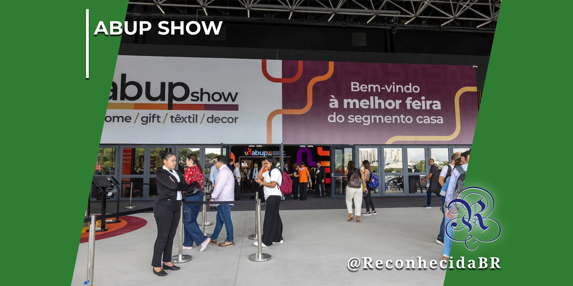 Fachada e entrada principal do evento Abup Show, exibindo um grande painel com a identidade visual da feira dividido em duas partes: à esquerda, o logotipo abupshow home gift têxtil decor; à direita, em fundo vinho, a frase Bem-vindo à melhor feira do segmento casa. Diversos visitantes e profissionais de terno caminham pela área de acesso em frente às portas de vidro. No canto superior esquerdo, há o selo "ABUP SHOW" em letras brancas; no inferior direito, o logotipo do portal Reconhecida com o @ReconhecidaBR.