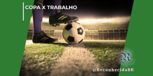 Close-up das pernas de um jogador de futebol vestindo meiões roxos e chuteiras pretas com listras brancas. O pé esquerdo está plantado no gramado e o pé direito está apoiado sobre uma bola de futebol clássica, branca e preta, posicionada em cima da linha branca de marcação do campo. Ao fundo, vê-se a arquibancada iluminada de um estádio de forma desfocada. No topo esquerdo, destaca-se o texto "Copa x Trabalho" e, no canto inferior direito, o logotipo clássico do portal Reconhecida com a assinatura @ReconhecidaBR.