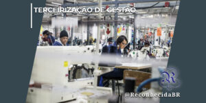Interior de uma fábrica têxtil ou confecção industrial com várias operárias trabalhando sentadas em fileiras diante de máquinas de costura industriais brancas. No centro, destaca-se uma mulher de óculos e cabelos escuros concentrada em seu trabalho. O ambiente exibe colunas metálicas, fiações suspensas e estruturas fabris ao fundo. No canto superior esquerdo, há o selo TERCEIRIZAÇÃO DE GESTÃO em letras brancas; no inferior direito, o logotipo do portal Reconhecida com o @ReconhecidaBR.