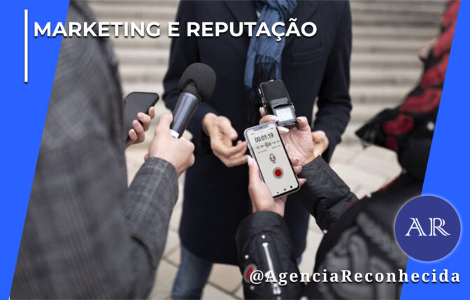 Uma pessoa ao centro vestindo casaco escuro e cachecol azul é abordada de perto por repórteres e jornalistas para uma entrevista na rua. Em primeiro plano, destacam-se as mãos dos repórteres segurando um microfone de reportagem preto, um gravador digital de áudio portátil e um smartphone que exibe na tela um aplicativo de gravador de voz ativo marcando 00:01:19. No canto superior esquerdo, aparece o selo MARKETING E REPUTAÇÃO em letras brancas; no canto inferior direito, destaca-se o logotipo redondo AR com o @AgenciaReconhecida.