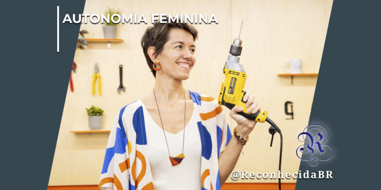 Mulher sorridente com cabelos curtos segura uma furadeira elétrica amarela em uma oficina com ferramentas ao fundo. No topo esquerdo, o texto "Autonomia Feminina" e, no canto inferior direito, o logotipo do portal Reconhecida com a marca d'água @ReconhecidaBR.