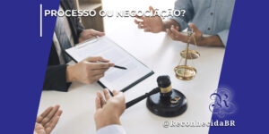 Vista superior de uma mesa branca onde um advogado de terno segura uma prancheta com documentos e aponta com uma caneta, enquanto duas pessoas gesticulam com as mãos em uma negociação. Sobre a mesa, destacam-se um martelo de juiz de madeira preta, um par de alianças douradas e uma pequena balança da justiça de metal. No topo esquerdo, há o texto "Processo ou Negociação?" e, no canto inferior direito, o logotipo clássico do portal Reconhecida com a assinatura @ReconhecidaBR.