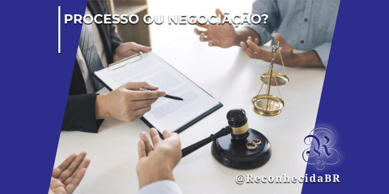 Vista superior de uma mesa branca onde um advogado de terno segura uma prancheta com documentos e aponta com uma caneta, enquanto duas pessoas gesticulam com as mãos em uma negociação. Sobre a mesa, destacam-se um martelo de juiz de madeira preta, um par de alianças douradas e uma pequena balança da justiça de metal. No topo esquerdo, há o texto "Processo ou Negociação?" e, no canto inferior direito, o logotipo clássico do portal Reconhecida com a assinatura @ReconhecidaBR.